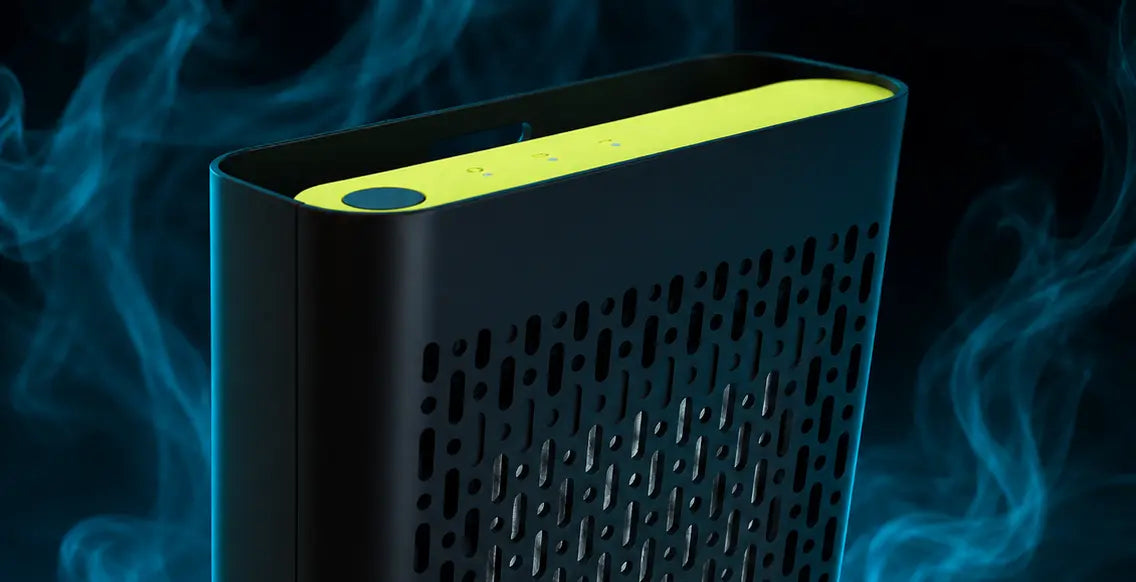 A sleek black DRIVE car air purifier with a bright yellow-green top panel and perforated side vents, shown against a dark background with blue smoke effects.